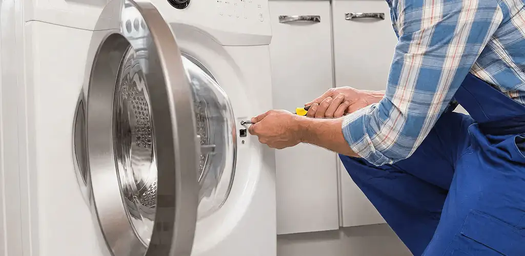 Handyman repairing a clothes dryer and checking electrical connections in Marietta, GA