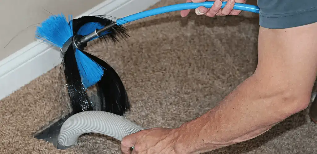 Dryer vent cleaning technician brushing lint from a vent line in Marietta, GA