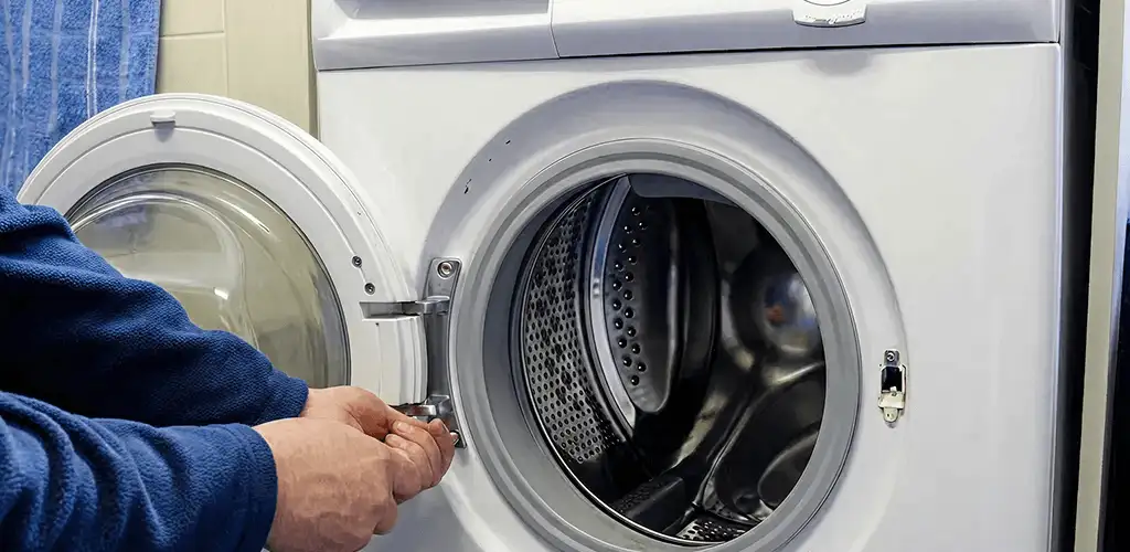Washing machine repair handyman checking a front-load washer door and latch in Marietta, GA