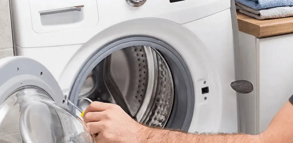 Handyman repairing a front-load washing machine and inspecting the drum in Marietta, GA