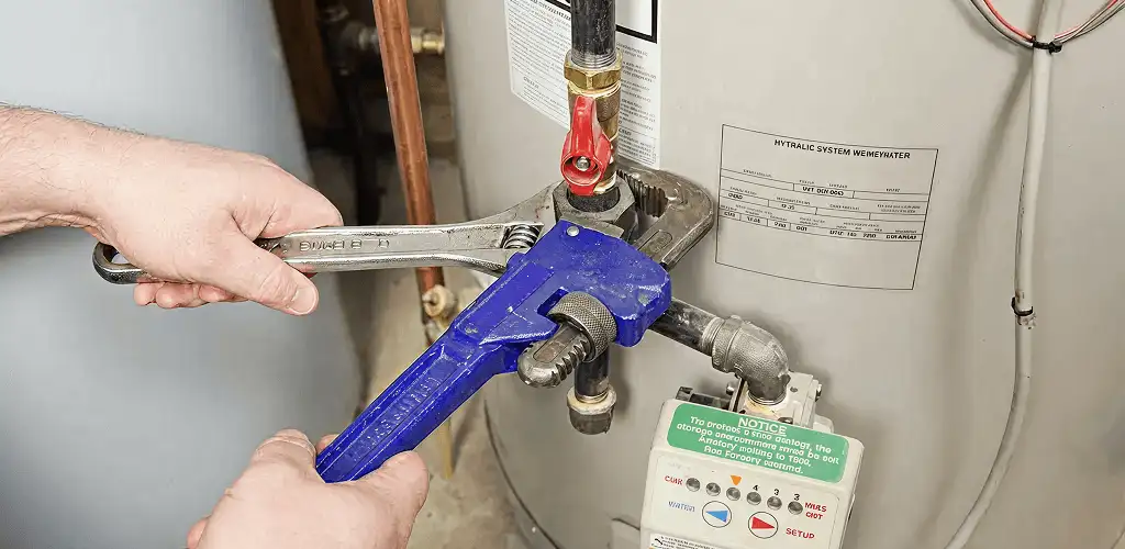 Water heater repair technician tightening the shutoff valve and supply line in Marietta, GA
